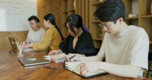 Students studying together in a classroom and taking notes. This is an ideal representation of students of the Overseas Koreans Scholarship in South Korea.